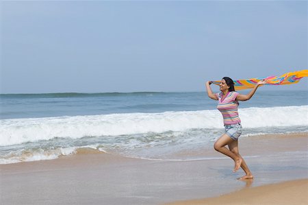 simsearch:630-01877039,k - Side profile of a young woman holding a stole and running on the beach Fotografie stock - Premium Royalty-Free, Codice: 630-01877057