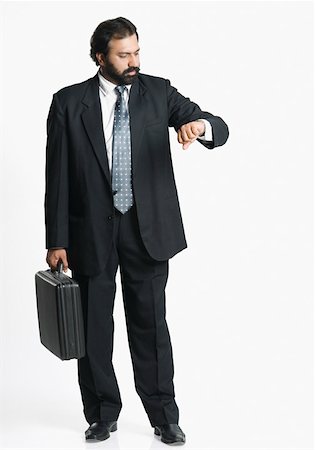 Businessman holding a briefcase and checking the time Stock Photo - Premium Royalty-Free, Code: 630-01877087