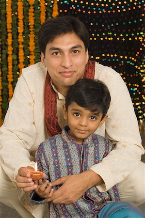 family celebrating diwali - Portrait of a young man and his son holding diwali lamps Stock Photo - Premium Royalty-Free, Code: 630-01877227