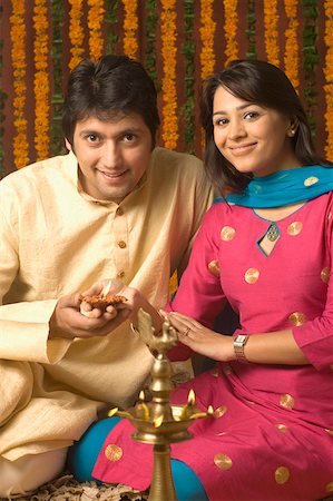 diwali couple images - Portrait of a mid adult man and a young woman holding a traditional diwali lamp and smiling Stock Photo - Premium Royalty-Free, Code: 630-01877312