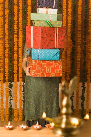 Young woman holding a stack of diwali gifts Stock Photo - Premium Royalty-Free, Code: 630-01877321