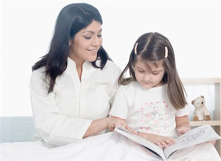 Mid adult woman reading a book with her daughter Stock Photo - Premium Royalty-Free, Code: 630-01877481