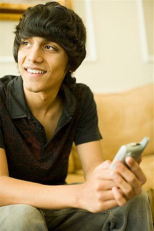 Teenage boy sitting on a couch and smiling Stock Photo - Premium Royalty-Free, Code: 630-01877705