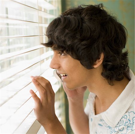 Side profile of a teenage boy looking through a window Stock Photo - Premium Royalty-Free, Code: 630-01877731