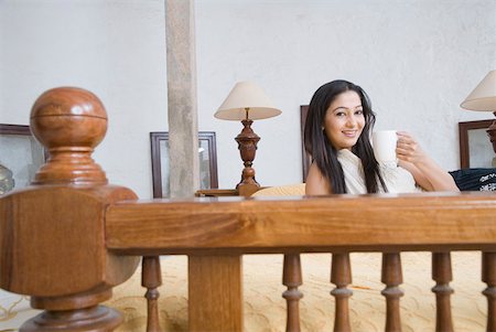 Portrait of a young woman holding a coffee cup and smiling Stock Photo - Premium Royalty-Free, Code: 630-01872158