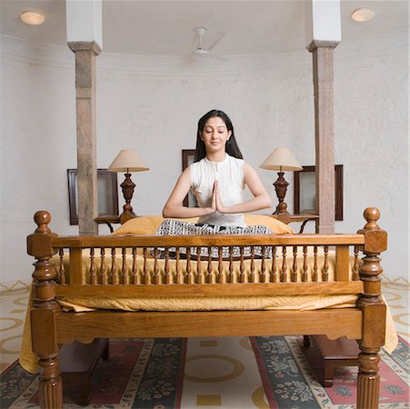 Jeune femme assise sur le lit dans une position de prière Photographie de stock - Premium Libres de Droits, Code: 630-01872164