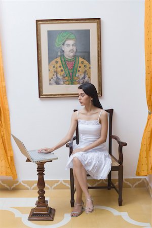 simsearch:630-02220797,k - Jeune femme assise avec les jambes croisées au niveau du genou et à l'aide d'un ordinateur portable Photographie de stock - Premium Libres de Droits, Code: 630-01872216
