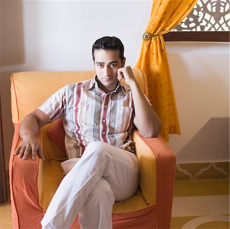 Portrait of a young man sitting in an armchair Stock Photo - Premium Royalty-Free, Code: 630-01872256
