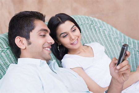 Close-up of a young couple looking at a mobile phone and smiling Stock Photo - Premium Royalty-Free, Code: 630-01872309