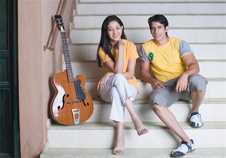 Portrait of a young couple sitting on a staircase and smiling Stock Photo - Premium Royalty-Free, Code: 630-01872335