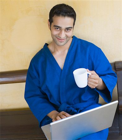 simsearch:630-01708665,k - Portrait of a young man holding a mug and using a laptop Stock Photo - Premium Royalty-Free, Code: 630-01872469