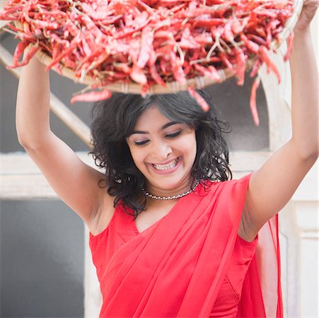 Young woman spraying red chili peppers from a basket Stock Photo - Premium Royalty-Free, Code: 630-01872487