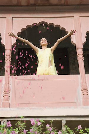 person spreading arms - Low angle view of a young woman spreading petals from the balcony of a fort, Neemrana Fort Palace, Neemrana, Alwar, Rajasthan, India Stock Photo - Premium Royalty-Free, Code: 630-01872542