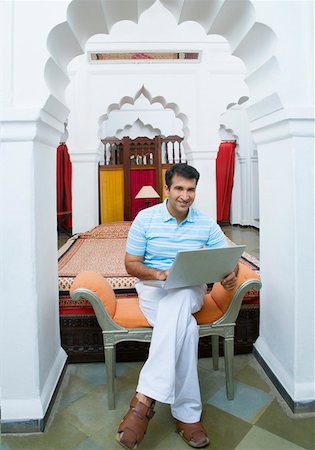 Portrait d'un homme adult moyen à l'aide d'un ordinateur portable et souriant Photographie de stock - Premium Libres de Droits, Code: 630-01872574