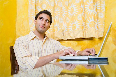 draperies glass - Young man using a laptop and thinking Stock Photo - Premium Royalty-Free, Code: 630-01872719