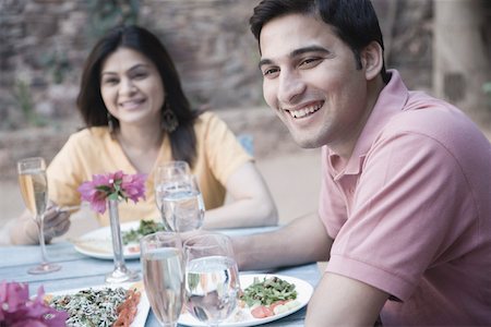 Close-up of a young man sitting with a mid adult woman at a dining table and smiling Stock Photo - Premium Royalty-Free, Code: 630-01872815