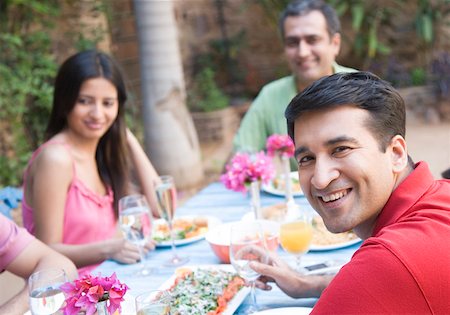 Portrait of a mid adult man with his friends sitting at a dining table Stock Photo - Premium Royalty-Free, Code: 630-01872817