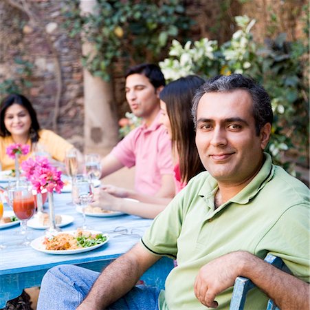 simsearch:630-01872828,k - Portrait of a mid adult man with his friends sitting at a dining table Foto de stock - Royalty Free Premium, Número: 630-01872820