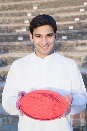 Portrait of a young man holding a plate of powder paint and smiling Stock Photo - Premium Royalty-Free, Code: 630-01872998