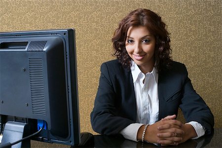 Portrait of a female receptionist sitting at a hotel reception and smiling Stock Photo - Premium Royalty-Free, Code: 630-01873171