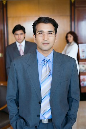 eye contact and camera - Portrait of a businessman standing with two business executives in the background Stock Photo - Premium Royalty-Free, Code: 630-01873208