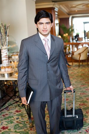 eye contact and camera - Portrait of a businessman pulling his luggage in a lobby Stock Photo - Premium Royalty-Free, Code: 630-01873234
