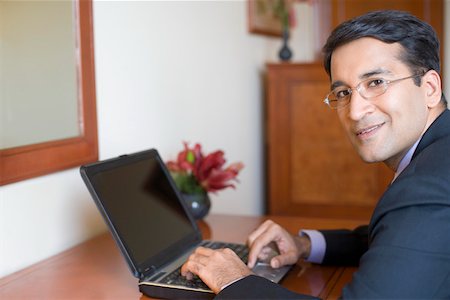 Portrait of a businessman using a laptop and smiling Stock Photo - Premium Royalty-Free, Code: 630-01873296