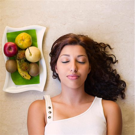 simsearch:630-01873358,k - High angle view of a young woman lying near a fruit tray Stock Photo - Premium Royalty-Free, Code: 630-01873357