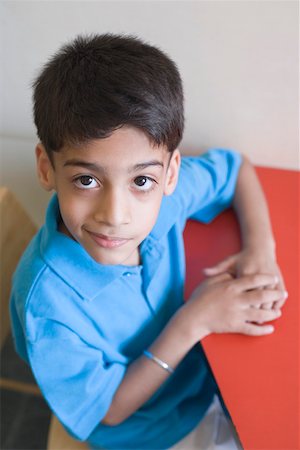 simsearch:630-01873478,k - Portrait of a schoolboy sitting at a table and smirking Foto de stock - Royalty Free Premium, Número: 630-01873426