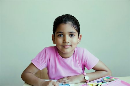 Portrait of a schoolgirl sitting at a table and drawing with crayons Stock Photo - Premium Royalty-Free, Code: 630-01873435