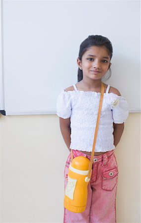 Portrait of a schoolgirl leaning against a wall in a classroom Stock Photo - Premium Royalty-Free, Code: 630-01873455