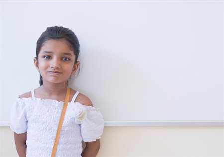 Portrait of a schoolgirl leaning against a whiteboard in a classroom Stock Photo - Premium Royalty-Free, Code: 630-01873456