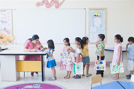 Vérifier les dessins des élèves en classe de l'enseignant Photographie de stock - Premium Libres de Droits, Code: 630-01873472