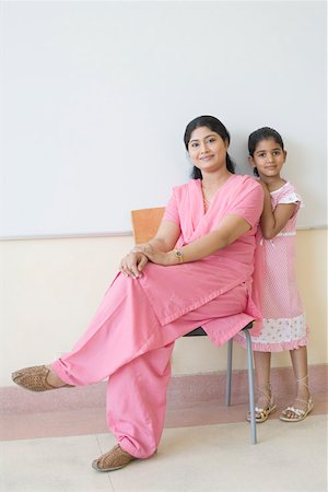 Portrait of a teacher sitting on a chair with a schoolgirl standing beside her Stock Photo - Premium Royalty-Free, Code: 630-01873496