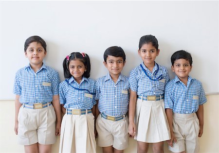 Portrait of five schoolchildren standing in front of a whiteboard and smiling Stock Photo - Premium Royalty-Free, Code: 630-01873524