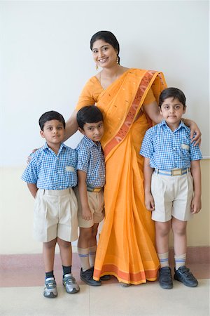 Portrait of a teacher standing with three schoolboys and smiling Stock Photo - Premium Royalty-Free, Code: 630-01873535