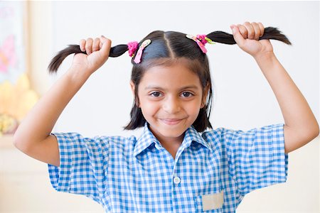 simsearch:630-01873578,k - Portrait of a schoolgirl holding her pigtails and smirking Fotografie stock - Premium Royalty-Free, Codice: 630-01873555