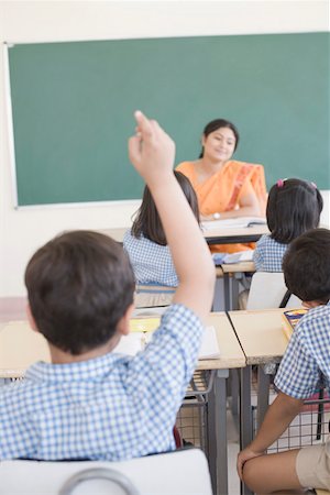 Rear view of a schoolboy in a classroom with his hand raised Stock Photo - Premium Royalty-Free, Code: 630-01873569