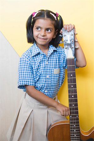 Schoolgirl holding a guitar and smirking in a music class Stock Photo - Premium Royalty-Free, Code: 630-01873624