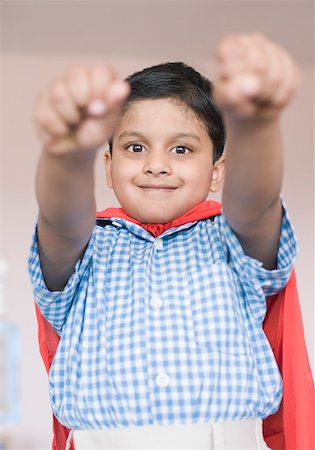 school boy hand up raised - Portrait of a boy imitating to be a superhero and smiling Stock Photo - Premium Royalty-Free, Code: 630-01873626