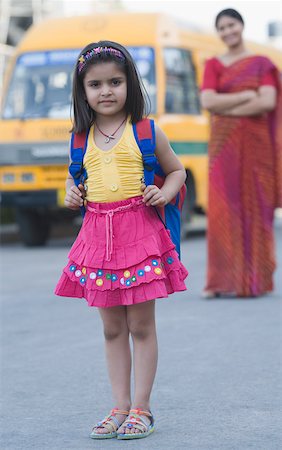 school bus - Portrait of a girl standing on the road with her teacher standing in the background Stock Photo - Premium Royalty-Free, Code: 630-01873700
