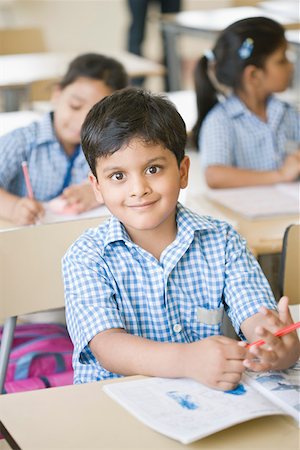 Portrait of a schoolboy sitting in a classroom and smiling Stock Photo - Premium Royalty-Free, Code: 630-01873779