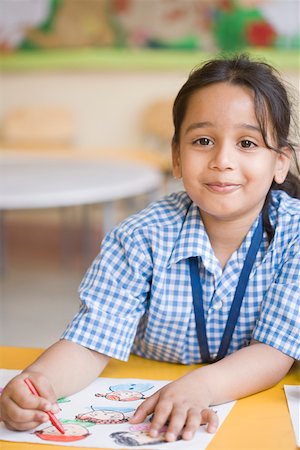 Schoolgirl sitting at a table and drawing with crayons Stock Photo - Premium Royalty-Free, Code: 630-01873772