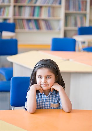 Schoolgirl sitting in a library and smiling Stock Photo - Premium Royalty-Free, Code: 630-01873794