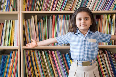 Portrait of a schoolgirl standing in a library with her arms outstretched Stock Photo - Premium Royalty-Free, Code: 630-01873798