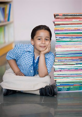 school boy sitting cross legged - Portrait of a schoolgirl sitting on the floor with a stack of books Stock Photo - Premium Royalty-Free, Code: 630-01873802