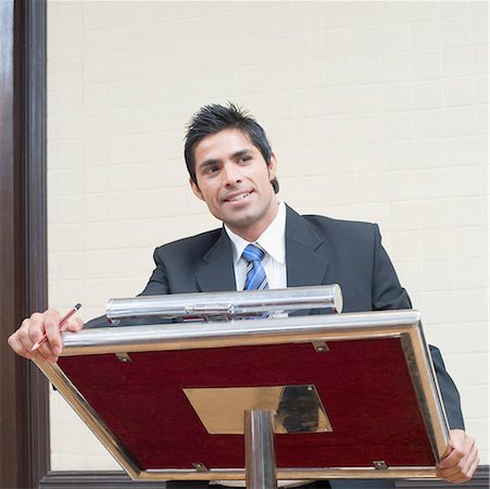 Businessman standing at a lectern and smiling Stock Photo - Premium Royalty-Free, Code: 630-01873868