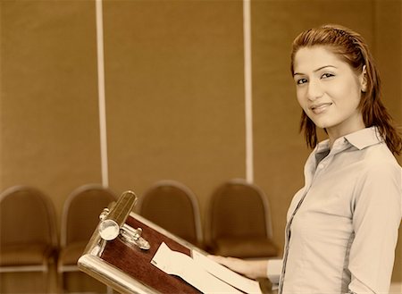 Portrait of a businesswoman standing at a lectern and smiling Stock Photo - Premium Royalty-Free, Code: 630-01873896