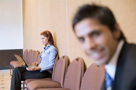 simsearch:630-01874091,k - Close-up of a businessman smiling with a businesswoman using a laptop in the background Fotografie stock - Premium Royalty-Free, Codice: 630-01873912