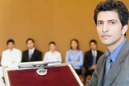 simsearch:630-01873857,k - Portrait of a businessman at a lectern with his colleagues in the background Foto de stock - Royalty Free Premium, Número: 630-01873937